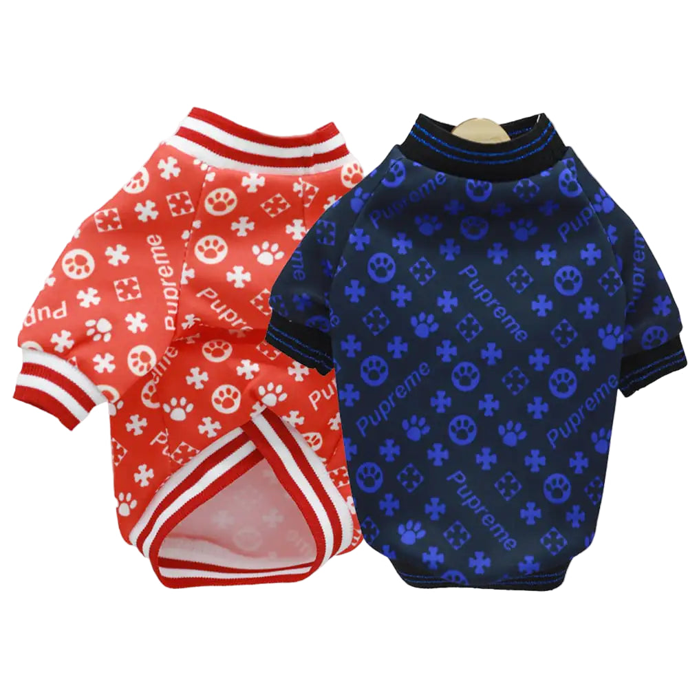 Two dog shirts, one red with white patterns and the other blue with black patterns, on a white background.
