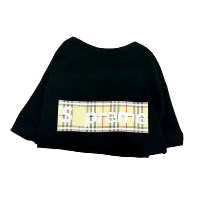 Black t-shirt with plaid design and 'Supreme' logo on a beige tote bag with brown handles.