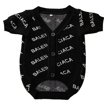 Black baby cardigan with white text on a green background