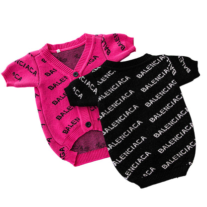 Pink and black baby outfits with Balenciaga branding on a green background
