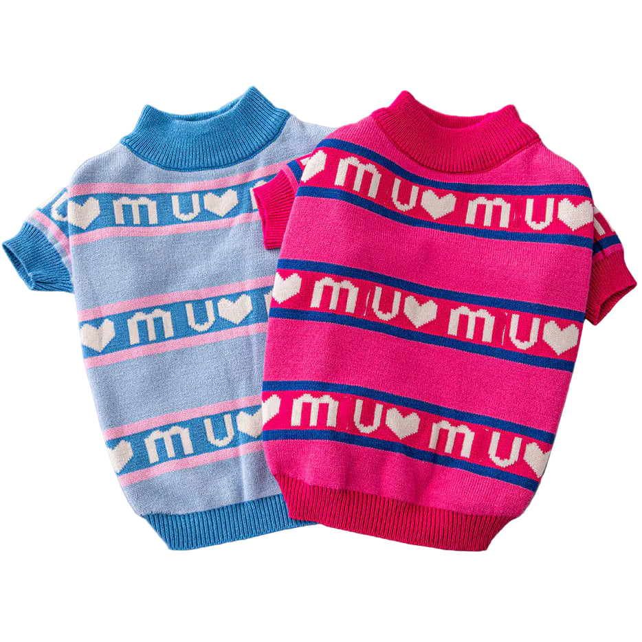 Two dog sweaters, one blue and one pink, on a gray surface.