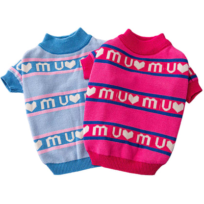 Two dog sweaters, one blue and one pink, on a gray surface.