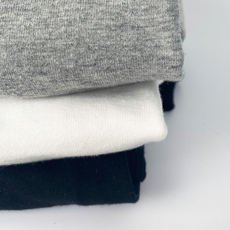 Stack of gray, white, and black shirts on a light gray background