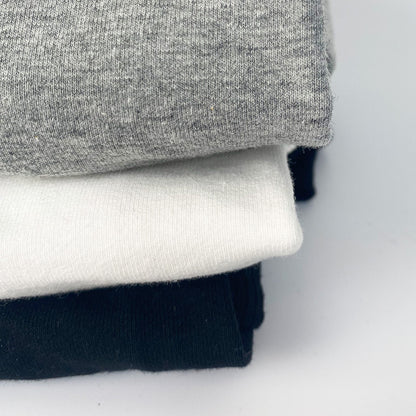Stack of gray, white, and black shirts on a light gray background